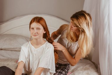 Mutlu bir aile. Gülümseyen bir anne sabah yatağında uyuduktan sonra kızının saçını örer. Anne kızını okula götürüyor. Etkileşim, temas, aşk.