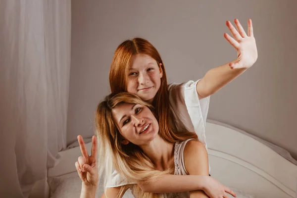 Feliz día de la madre. Mamá y su hija están jugando a las chicas, sonriendo y abrazándose en la cama. Vacaciones en familia y unión . — Foto de Stock