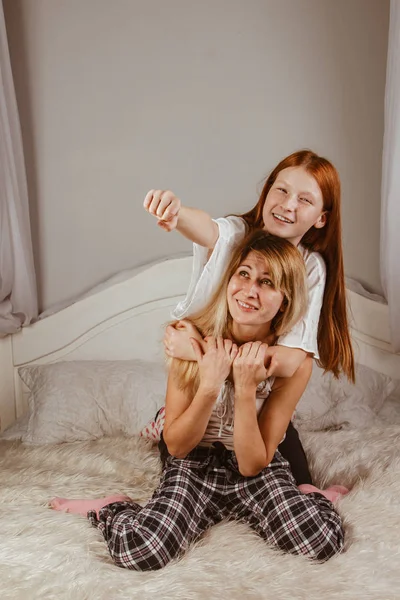 Feliz día de la madre. Mamá y su hija están jugando a las chicas, sonriendo y abrazándose en la cama. Vacaciones en familia y unión . — Foto de Stock