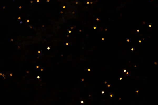 Goldene abstrakte gelbe, orangefarbene Bokeh-Lichter isoliert auf schwarzem Hintergrund mit Kopierraum. Urlaubs- und Weihnachtszeit-Konzept, grafische Ressourcen, Grußkarte. Tapete. Vielfarbige Lichter. — Stockfoto