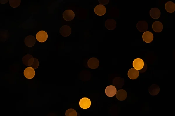 金色の抽象的な黄色、オレンジ色のボケのライトは、コピースペースと黒の背景に隔離されます。休日やクリスマスシーズンのコンセプト、グラフィックリソース、グリーティングカード。壁紙多色灯. — ストック写真
