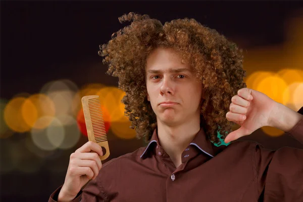 Celebration, people and holidays concept - happy curly guy having a Christmas or New Year party on the background of festive lights. Unhappy with the gift. — ストック写真