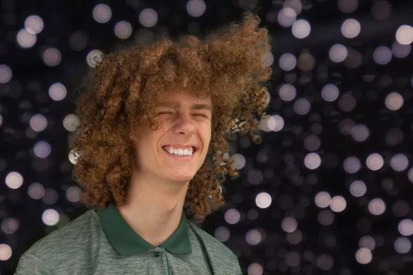 Celebration, people and holidays concept - happy curly guy having a Christmas or New Year party on the background of festive lights. — ストック写真