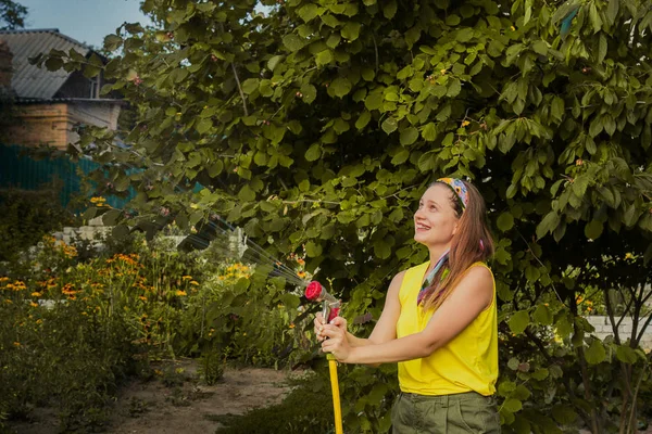 Zomer Tuin, drenken - mooi meisje drenken rozen met tuin slang in de tuin. — Stockfoto