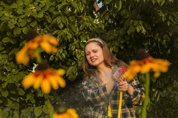 Jeune jolie fille s'amuser dans le jardin arrosant les plantes avec un tuyau. Sourire tout en prenant un passe-temps préféré . — Photo