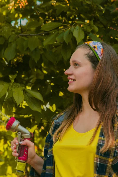 Jong mooi meisje hebben plezier in de tuin besproeien planten met een slang. Lachen tijdens het nemen van een favoriete hobby. — Stockfoto