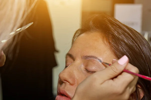 Косметолог - визажист рисует хну на ранее выщипанных, дизайнерских, подстриженных бровях в салоне красоты во время коррекции сессии. Профессиональный массаж лица . — стоковое фото
