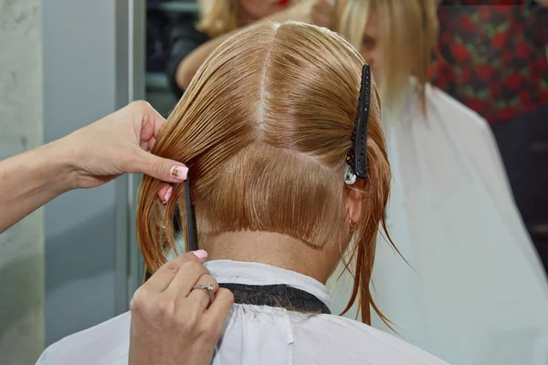 Kvinna med medellångt blont hår. Med en kort frisyr hos frisören på stylisten med hjälp av sax. Skötselåtgärder. Mästaren förkortar sitt hår. — Stockfoto