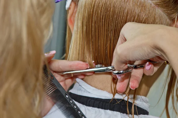 Kvinna med medellångt blont hår. Med en kort frisyr hos frisören på stylisten med hjälp av sax. Skötselåtgärder. Mästaren förkortar sitt hår. — Stockfoto