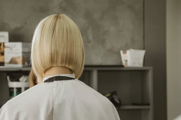 O close-up de um cabeleireiro corta o cabelo branco molhado de um cliente em um salão. O cabeleireiro corta uma mulher. Vista lateral de um cabelo de corte de mão com tesoura . — Fotografia de Stock