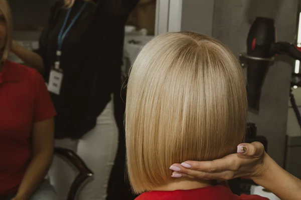 O close-up de um cabeleireiro corta o cabelo branco molhado de um cliente em um salão. O cabeleireiro corta uma mulher. Vista lateral de um cabelo de corte de mão com tesoura . — Fotografia de Stock