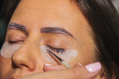 Güzellik tedavisi. Kirpikleri boyalı, yakın plan kadın yüzü. Kirpikleri kaplama. Yan görünüm.