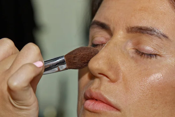 Dziewczyna maluje proszek na twarzy, uzupełnia smokey makijaż oczu w salonie piękności. Profesjonalna pielęgnacja skóry. — Zdjęcie stockowe