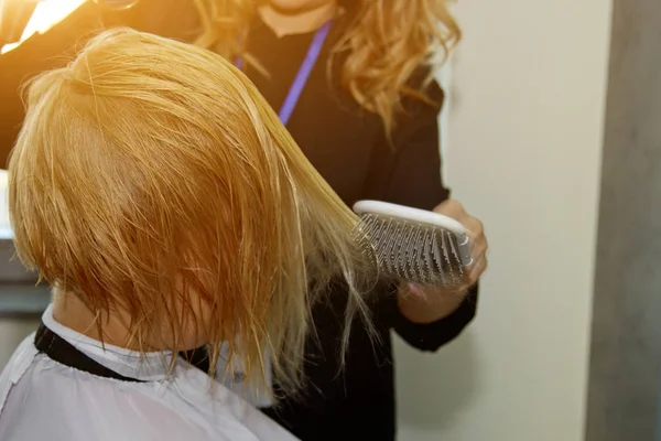 Närbild av frisör händer torkar mänskligt hår med utrustning. Kvinnan håller i en kam. närbild. Makrofoto. — Stockfoto