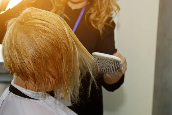 Close up of hairdresser hands drying human hair with equipment. Woman holding a comb. close-up. Macro photo. — Stock Photo, Image