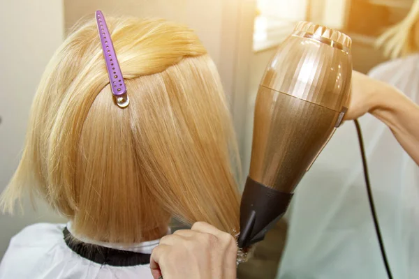 Close-up de mãos de cabeleireiro secar o cabelo humano com equipamento. Mulher segurando um pente. close-up. Macro foto . — Fotografia de Stock