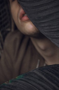 Yeşil yapraklı genç bir adamın portresi. İyi bir adam yeşil bitkilerden oluşan bir duvara karşı duruyor. Sarmaşık çalılıkları içinde beyaz bir adamın yakın çekim.