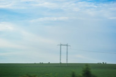 Yüksek voltajlı elektrik iletim pilonu silueti yerleştirildi. Mavi gökyüzüne karşı elektrik iletim pilonu silueti. Mavi gökyüzü arka planında yüksek voltajlı elektrik kulesi, yan görünüm.