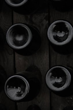 Şarap şişelerinin dibi açık havada raflarda sergileniyor. Yaratıcı karanlık ve soyut bir arkaplan. Alkol kavramı.