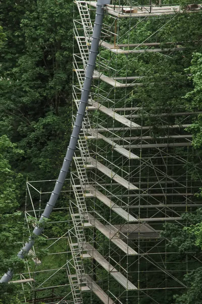 Construcción de un edificio utilizando andamios. El marco metálico de un edificio inacabado ubicado en un parque industrial abandonado. Producción, construcción, industria . — Foto de Stock