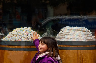 Yanlış ısırığı olan sevimli küçük bir kız, şekerci dükkanının yanında duruyor. Kızı şeker satın almak istiyor. Çocuklarda diş sorunu kavramı.