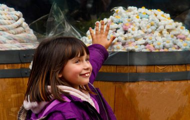 Yanlış ısırığı olan sevimli küçük bir kız, şekerci dükkanının yanında duruyor. Kızı şeker satın almak istiyor. Çocuklarda diş sorunu kavramı.