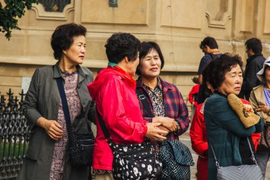 Prag 'da. 10.05.2019: Asyalı turistler şehrin ana caddesinde yürüyorlar. Yoldan geçenler manzaranın fotoğrafını çeker ve selfie çeker..
