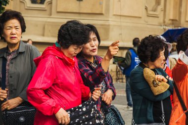 Prag 'da. 10.05.2019: Asyalı turistler şehrin ana caddesinde yürüyorlar. Yoldan geçenler manzaranın fotoğrafını çeker ve selfie çeker..