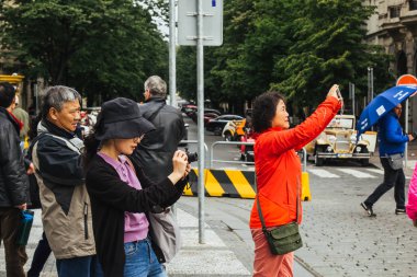 Prag 'da. 10.05.2019: Asyalı turistler şehrin ana caddesinde yürüyorlar. Yoldan geçenler manzaranın fotoğrafını çeker ve selfie çeker..