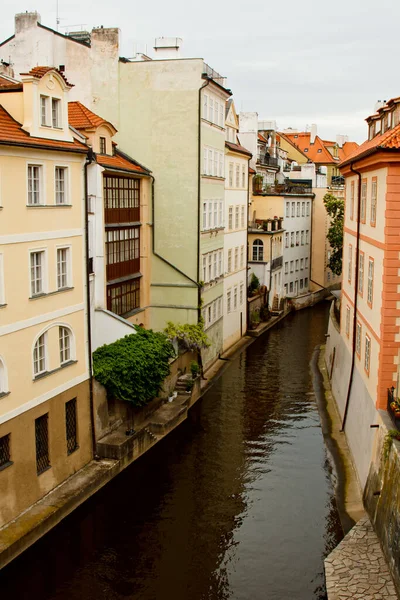 Praga. 05.10.2019: Strada con case di fiori gialli e beige, attraverso cui scorre il piccolo fiume Moldava. Con un bel tramonto dorato . — Foto Stock