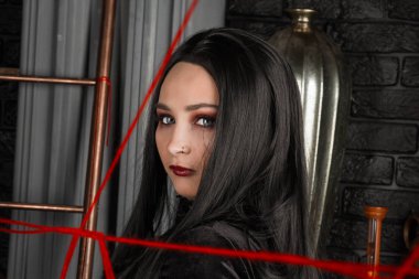 Uzun saçlı, siyah elbiseli, mutlu, büyük beden bir manken sandalyede oturuyor. Kırmızı iplikli, tombul genç bir kadın, bowling konsepti. Vücut pozitif. Tek bir güzellik kavramı. Xxxl modası