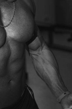 Siyah beyaz fotoğraf. Güçlü erkek pazıları yakın plan. Spor salonu. Vücut geliştirici. Güzel, şişmiş erkek vücudu. Antrenör, reklamcılık, sağlıklı yaşam tarzı. Vücut geliştirici. Spor konsepti