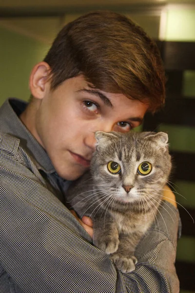 Teen guy hugs a cat. Holds the animal in his arms. Portrait. The concept of friendship of man and animal. Allergy to wool