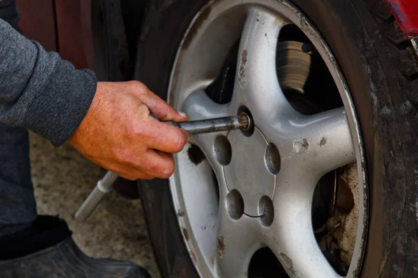 Auto mechanic man with electric screwdriver changing tire outside. Car service. Hands replace tires on wheels. Tire installation concept