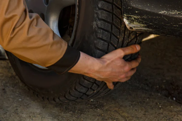 A mechanic removes a car tire. A man working on a machine to remove rubber from a wheel disk