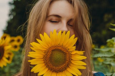 Sarışın ve ayçiçeği çiçekli güzel, tatlı, seksi bir kızın yakın plan portresi. Zevk duygusu, özgürlük konsepti, yaşam tarzı. Kapalı gözler
