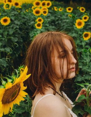 Beyaz elbiseli, ayçiçeği çiçekli, güzel, seksi, kızıl saçlı bir kızın portresi. Zevk duygusu, özgürlük konsepti, yaşam tarzı