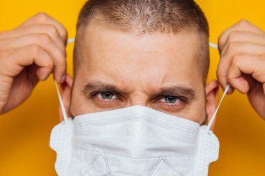 Koronavirüs karantinası sırasında tıbbi maske takan sakallı beyaz bir adamın fotoğrafını çek. Yüzün ön kısmı hafifçe bulanıklaştı. Coronavirus, COVID-19 salgını. Doktor, hemşire konsepti