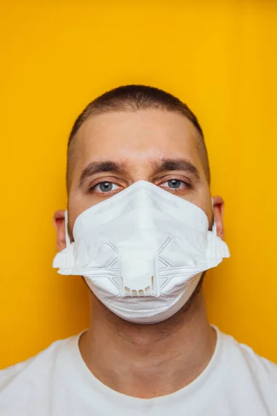 Corona virus. Young guy in a respirator on a yellow background. Protection of the mouth and eyes from viruses, infections, exhaust fumes. Methods for the prevention of infection