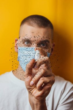 Sarı arka planda maskeli bir gencin portresi. Ellerini antiseptikle dezenfekte ediyor. Böcek ilaçlama. Coronavirus konsepti. Mikrop ve virüslere karşı koruma