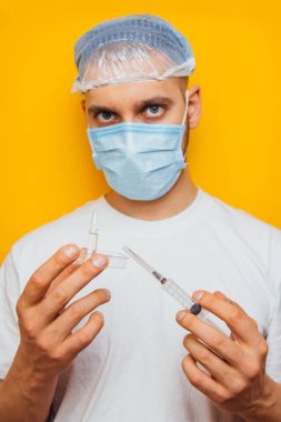 Aşıyla grip şırıngası tutan bir araştırmacı ya da bilim adamı. Sarı arka planda izole edilmiş. Kavramsal fotoğraf, sosyal sorunlar