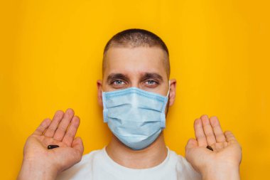 Maskeli adam elinde koronavirüsten bir hap tutuyor. Bağışıklık sistemini güçlendirmek için vitaminler. Evinde otur. Soğuk algınlığı, grip, virüs, karantina, salgın konsepti. Zor seçim.