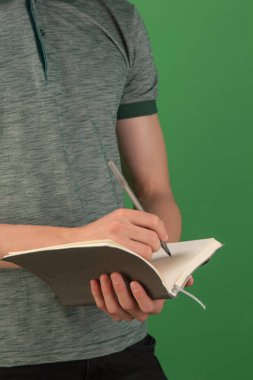 Dizüstü bilgisayarı olan genç bir adam çevrimiçi eğitimle meşgul. Kıvırcık saçlı yakışıklı bir adam elinde açık bir defter tutuyor ve üzerinde çalışıyor. Bilgi, teknoloji konsepti. Karantina