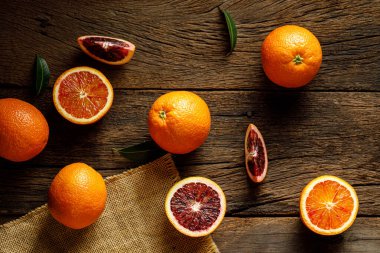 Dilimlenmiş Sicilya kanı, eski, siyah ahşap arka planda meyve portakalı bırakır. Üst görünüm.