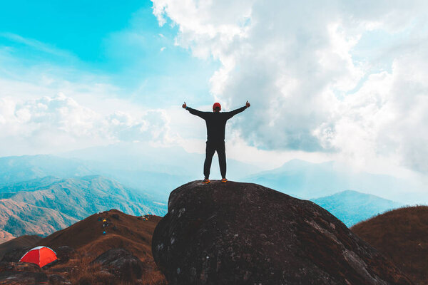Silhouette of man hold up hands on the peak of mountain,success concept