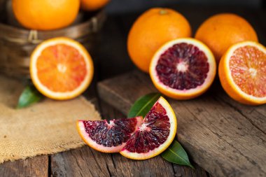 Dilimlenmiş Sicilya kanı, eski, siyah ahşap arka planda meyve portakalı bırakır. Üst görünüm.