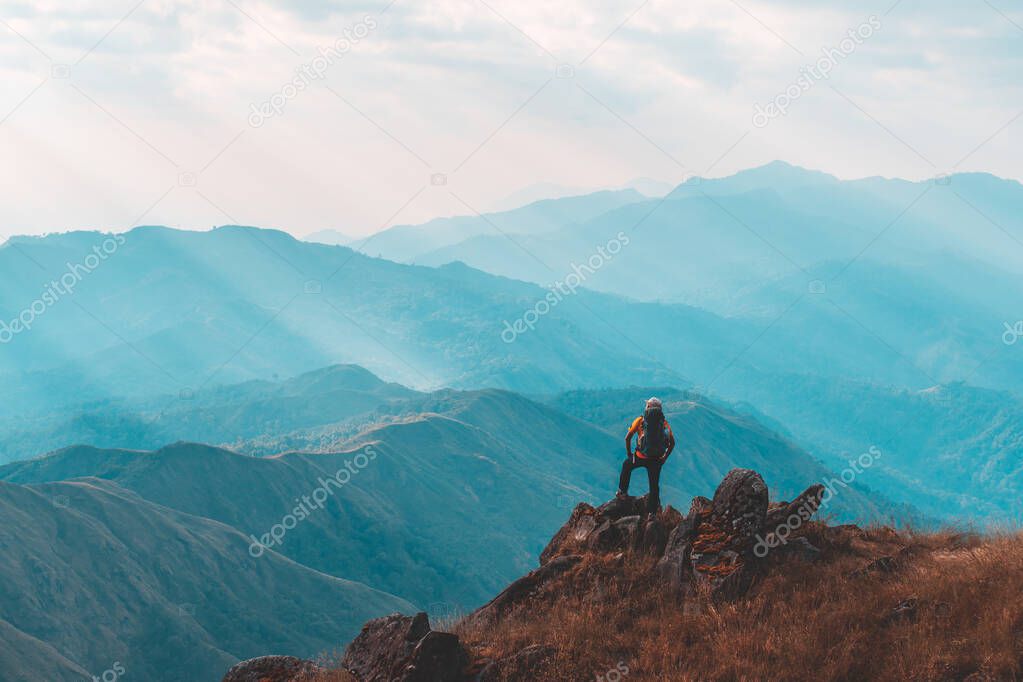 Silhouette of man hold up hands on the peak of mountain,success concept