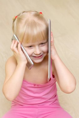 küçük kız bir pembe elbise gülümseme ve cep telefonuyla konuşuyor ve 