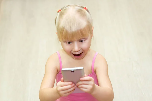 Маленькая девочка в розовом платье, напуганная мобильным телефоном Стоковое Изображение