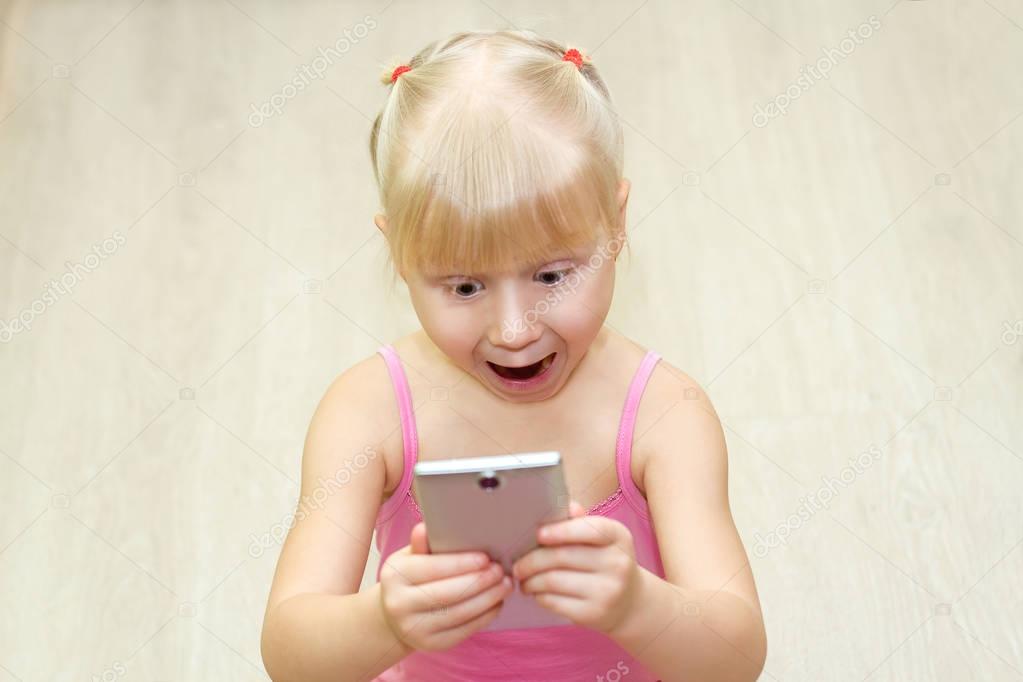 little girl in a pink dress scared with mobile phone